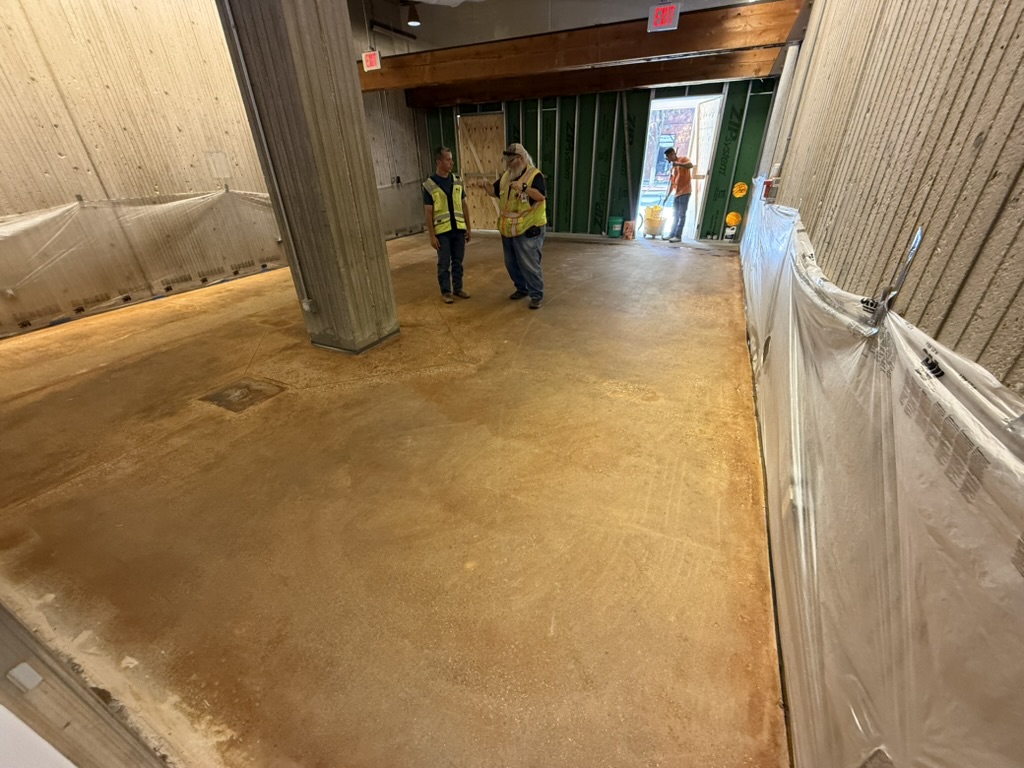 Team walking the bare concrete floor and protected walls before work begins